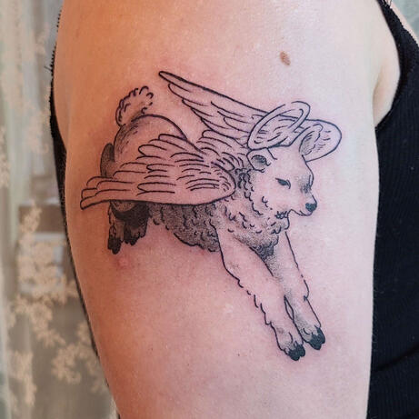 black tattoo of a leaping lamb with angel wings and a halo