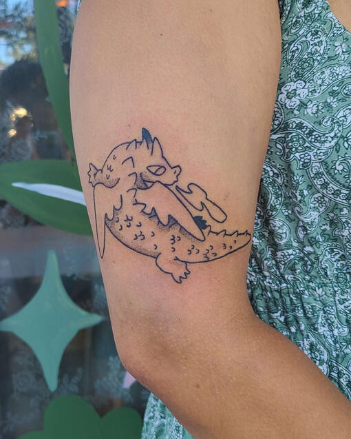 black line tattoo of a cartoon dragon.